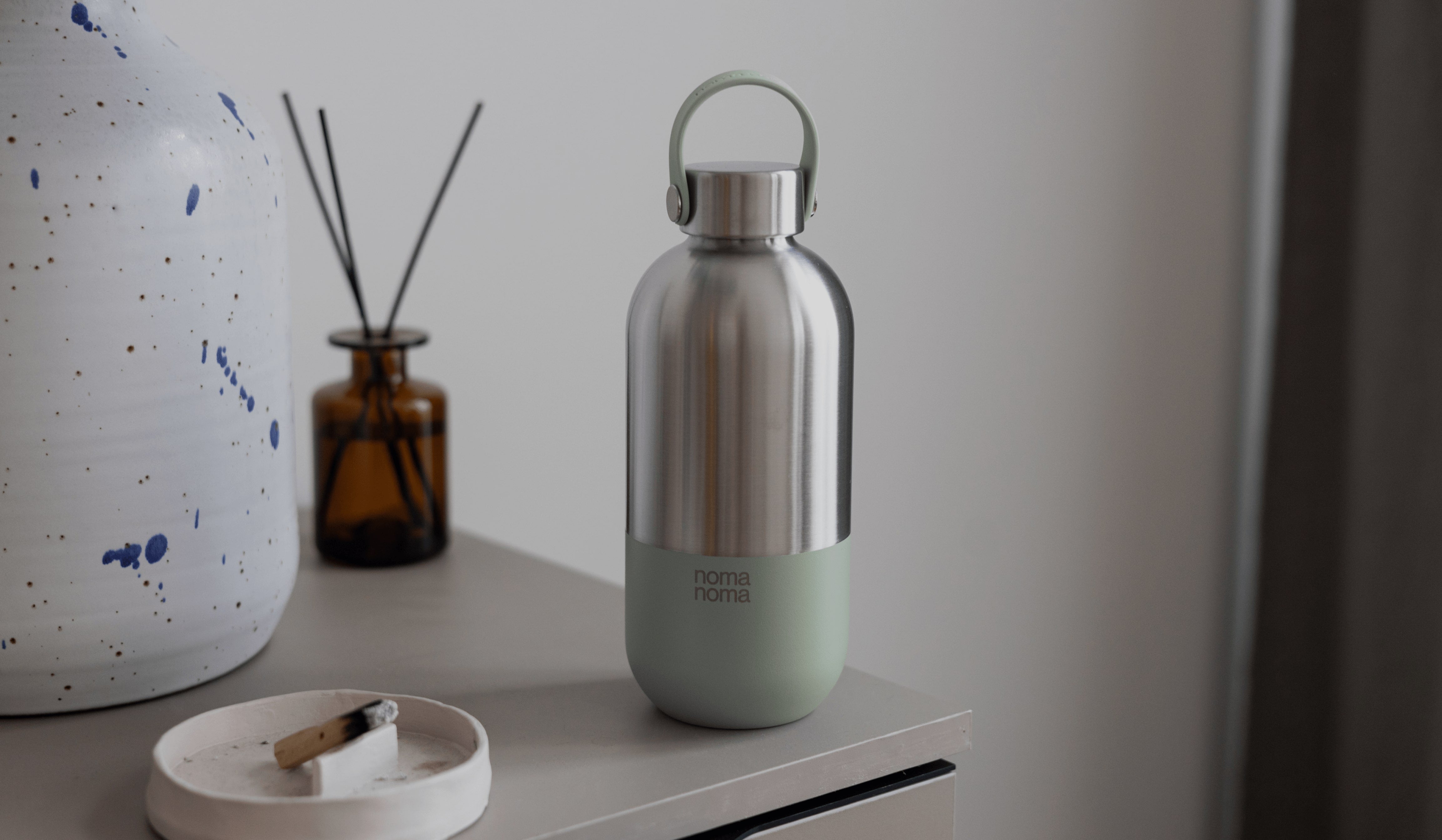 Die noma noma Edelstahl Trinkflasche (750ml - matcha green) auf einem Schrank stehend
